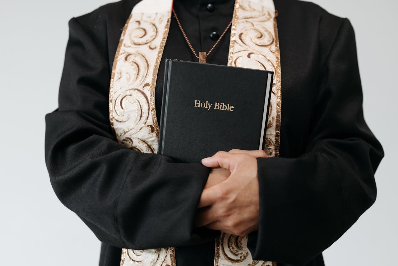 Close-up of a religious figure in vestments holding the Holy Bible, symbolizing faith and spirituality.